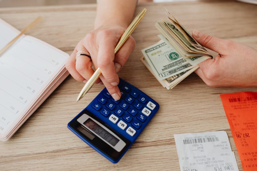 Person using a calculator next to cash and receipts
