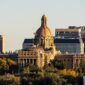 Alberta Legislature Building's domed sandstone facade in Edmonton, lit by evening sun above autumn trees