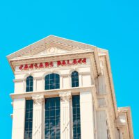 Caesars Palace hotel tower with red lettering against a bright blue sky
