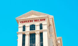 Caesars Palace hotel tower with red lettering against a bright blue sky