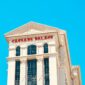 Caesars Palace hotel tower with red lettering against a bright blue sky