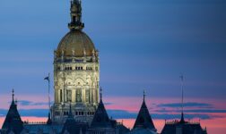 Connecticut State Capitol's gilded dome lit at dusk against a pink and blue sky