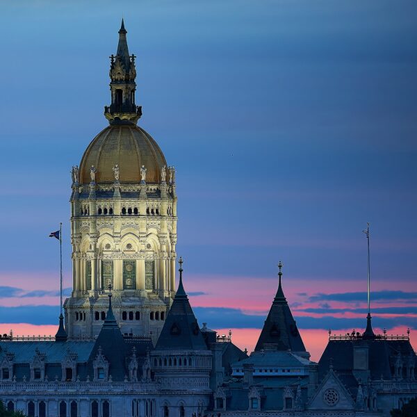 Connecticut State Capitol's gilded dome lit at dusk against a pink and blue sky