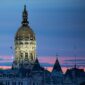 Connecticut State Capitol's gilded dome lit at dusk against a pink and blue sky