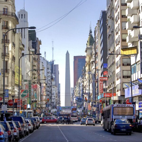 Busy downtown Buenos Aires street lined with buildings, the Obelisco visible in the distance
