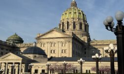 Pennsylvania State Capitol's green-tiled dome and stone facade in Harrisburg, lit by evening sun