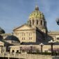 Pennsylvania State Capitol's green-tiled dome and stone facade in Harrisburg, lit by evening sun