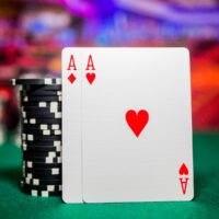 Pair of aces leaning on a stack of black poker chips on a green felt card room table